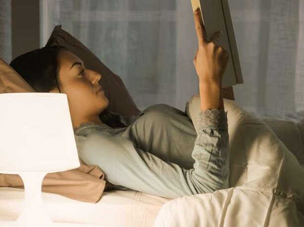 Energie-Paket Frau im Bett mit Nachttischlampe liest Buch